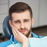 Man in dental chair holding cheek