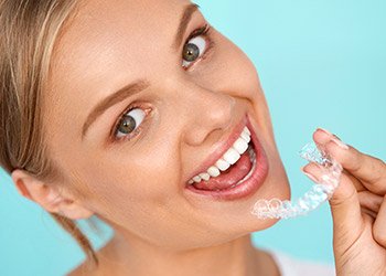 Smiling woman placing Invisalign tray