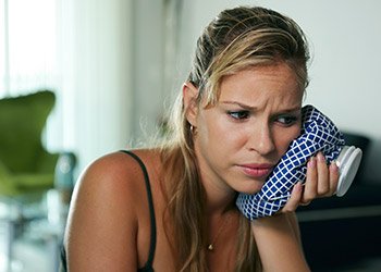 Woman holding ice pack to cheek