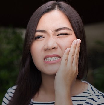 Woman holding cheek in pain