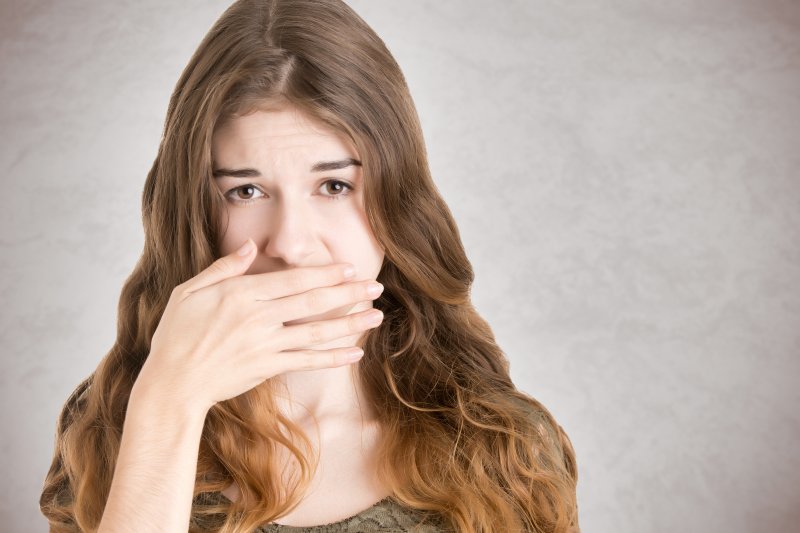 Woman embarrassed at the dentist covering her mouth