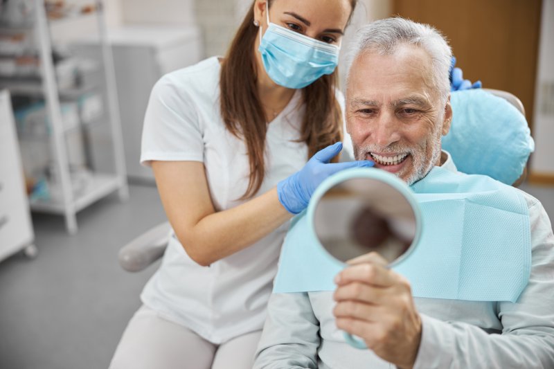 older man looking at his new dental implants