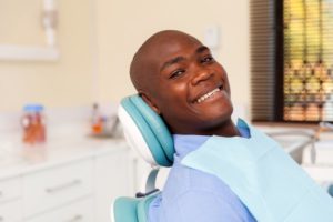 a man smiling at a dental checkup and ready to ask his dentist questions 