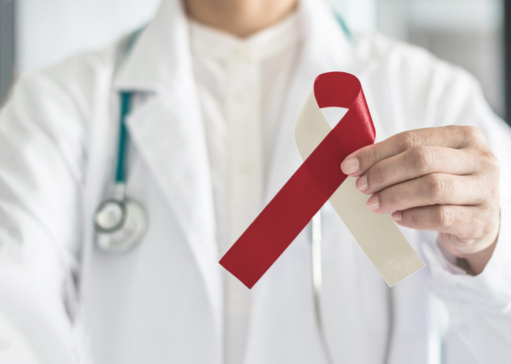 Doctor holding up red and white ribbon for oral cancer awareness